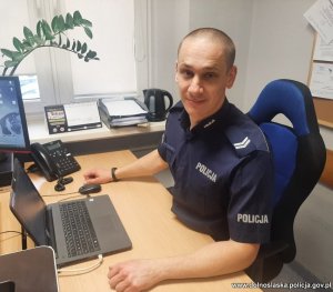 policjant siedzący w mundurze przy biurku