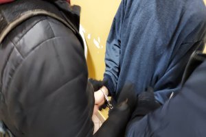 policjant zakłada zatrzymanemu kajdanki na ręce