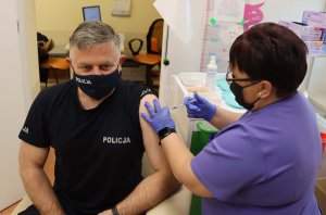 umundurowany policjant przyjmuje szczepionkę przeciwko koronawirusowi