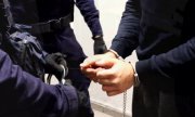 policjant zakłada zatrzymanemu mężczyźnie kajdanki zespolone