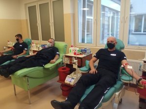 Trzech funkcjonariuszy w pomieszczeniu centrum krwiodawstwa  podczas oddawania krwi