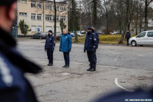 troje umundurowanych policjantów stoi na placu znajdujący się między nimi mężczyzna w niebieskiej kurtce stoją na przeciwko policjantów