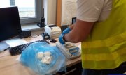 policjant waży na wadze elektronicznej zabezpieczoną amfetaminę