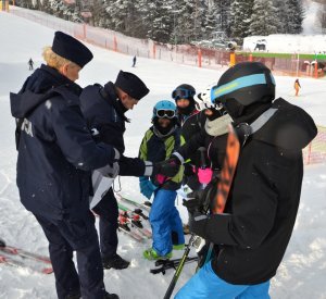 policjanci wręczają ulotki i odblaski narciarzom