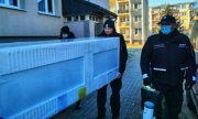 Policjanci wnoszą lodówkę do mieszkania w bloku