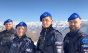 Czterej policjanci w niebieskich beretach na tle masywu górskiego.