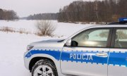 policyjny radiowóz stoi na ośnieżonej drodze przy zalewie pokrytym lodem i śniegiem