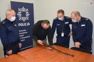Policjanci przyglądają się, jak dyrektor muzeum sprawdza zamek broni