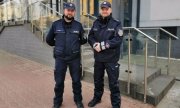 Dwóch umundurowanych policjantów stojących przed budynkiem komendy