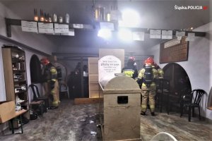Funkcjonariusze straży pożarnej w pomieszczeniu, które się paliło