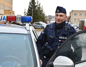 policjant stoi obok radiowozu policyjnego