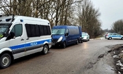 Policyjny radiowóz, za nim niebieski bus i samochód Straży Granicznej