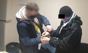 Ubrany po cywilnemu policjant zakłada kajdanki zatrzymanemu mężczyźnie