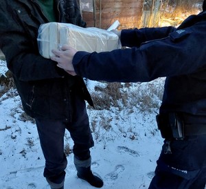 policjantka przekazuje mężczyźnie paczkę z opałem