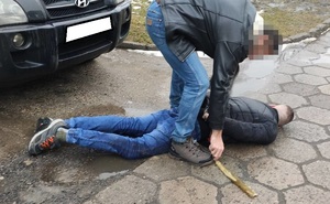 nieumundurowany policjant zakłada kajdanki leżącemu mężczyźnie