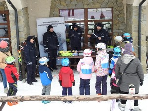 Policjanci przy stoisku profilaktycznym z grupą dzieci.
