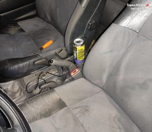 Wnętrze samochodu osobowego, pomiędzy siedzeniami otwarta puszka piwa