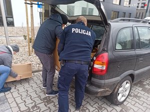 policjant i radny pakują nakrętki do samochodu