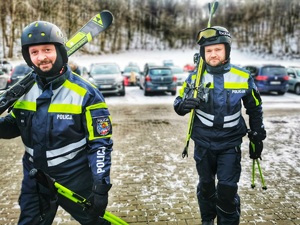 dwóch policjantów stoi na parkingu przed stokiem narciarskim
