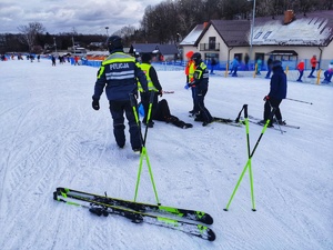funkcjonariusze pomagają poszkodowanemu na stoku narciarskim