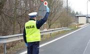 policjant z ruchu drogowego z uniesioną dłonią do zatrzymania pojazdu