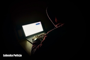 Mężczyzna w ciemnym pokoju przed monitorem laptopa