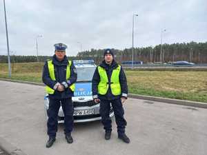 dwaj policjanci, którzy eskortowali 9-ciomiesięczne dziecko do szpitala w Szczecinie, od lewej sierż. szt. Mirosław Pawelec i post. Grzegorz Idziaszek na tle radiowozu oznakowanego Kia Ceed
