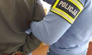 policjant z zatrzymanym mężczyzną w kajdankach