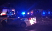 Zdjęcie kolorowe: zdjęcie wykonane w nocy. Widoczny radiowóz policyjny z włączonymi sygnałami świetlnymi, w tle karetka pogotowia i wóz straży pożarnej