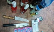 Zdjęcie przedstawia dwa noże zabezpieczone przez policjantów u podejrzanego. Na zdjęciu znajdują się również skradzione produkty w postaci alkoholi i gum do żucia