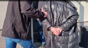 policjant prowadzi zatrzymaną kobietę w kajdankach