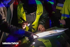 Policjanci przeglądają mapę świecąc latarką