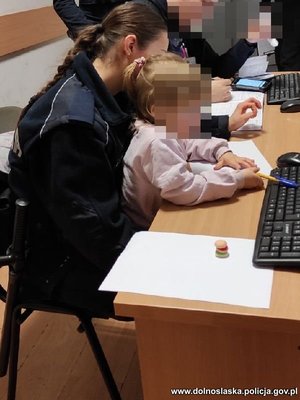 policjantka siedzi z dziewczynką na kolanach przy biurku