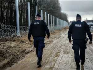 policjanci idą wzdłuż budowy zapory granicznej