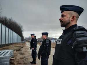 policjanci stoją naprzeciwko budowy zapory granicznej