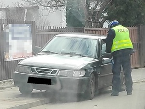 policjant stoi przy samochodzie osobowym