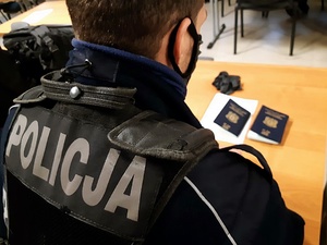 policjant siedzi przy stole, na którym leżą paszporty