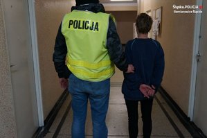 policjant prowadzi zatrzymaną kobietę