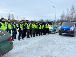 polscy i litewscy policjanci pozują do zdjęcia grupowego, obok stoją radiowozy