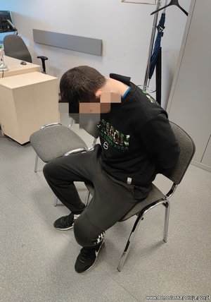 mężczyzna w kajdankach siedzi na krześle w pokoju