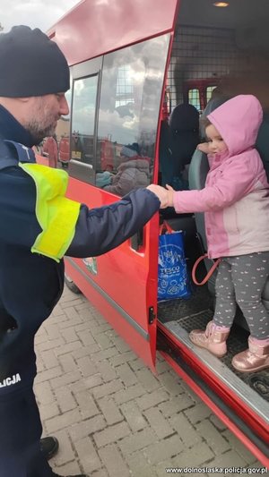 policjant pomaga dziecku wyjśći z busa