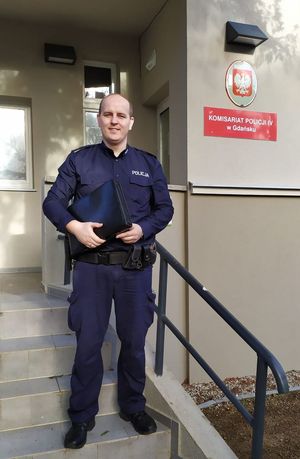 policjant stoi na schodach do komisariatu Policji