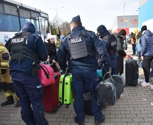 Policjanci pomagają uchodźcom w przenoszeniu bagażu