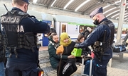 zdjęcie kolorowe: policjanci katowickiego oddziału prewencji rozdający jedzenie oczekującym na peronie uchdźcom
