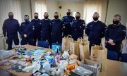 Policjanci stojący przy stole na którym znajdują się zebrane dla uchodźców z Ukrainy przedmioty