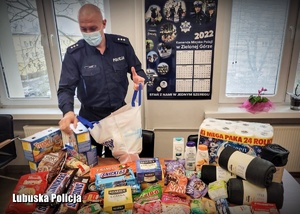 Policjant stojący pakuje artykuły spożywcze do torby