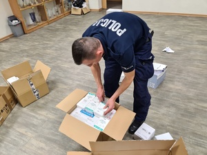 policjant układa kartoniki z bandażami w kartonie
