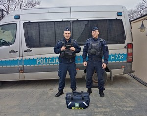 Zdjęcie kolorowe przedstawia dwóch umundurowanych funkcjonariuszy Policji, którzy uratowali życie kobiece jadącej w pociągu  relacji Przemyśl-Kraków