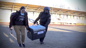 policyjny lotnik razem z kobietą niosą lodówkę z organem do przeszczepu