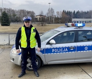 umundurowany policjant ruchu drogowego stoi przed radiowozem